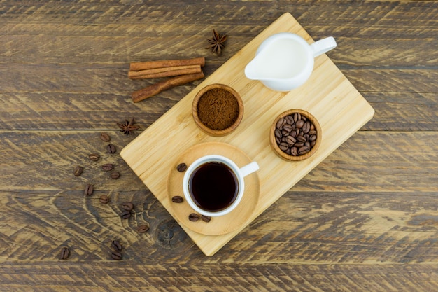 Vista superior da bandeja de madeira com xícara expresso, variedade de café e leiteiro com leite. fundo de madeira marrom.