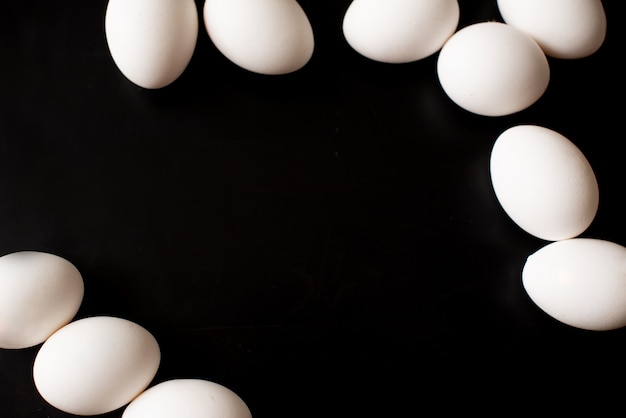 Foto vista superior da caixa aberta com os ovos no fundo preto.