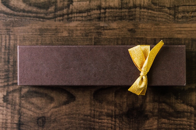 Vista superior da caixa de papel marrom do chocolate do retângulo que amarra com fita dourada.