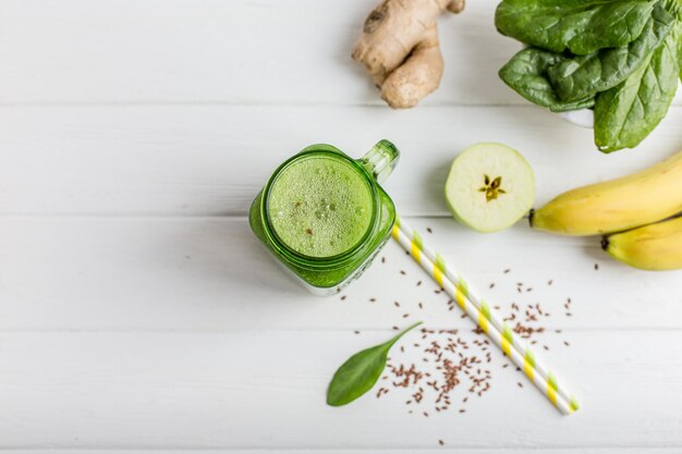 Vista superior da caneca cheia de smoothie verde e ingredientes na mesa de madeira Comida vegetariana