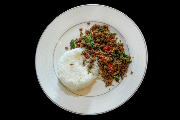 Vista superior da carne picada com manjericão tailandês no foco de arroz seletivo