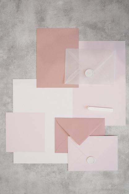 Vista superior da composição de folhas coloridas de papel branco e rosa envelopes selados com cera branca s