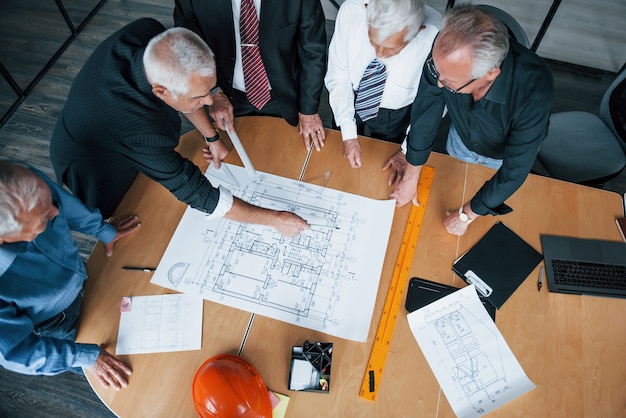 Foto vista superior da equipe envelhecida de arquitetos idosos empresário tem uma reunião no escritório e trabalha com o plano.