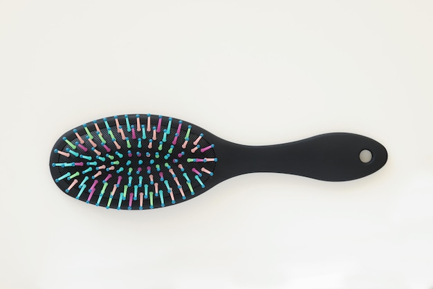 Foto vista superior da escova de cabelo de plástico preto com pontas coloridas na mesa em formato redondo