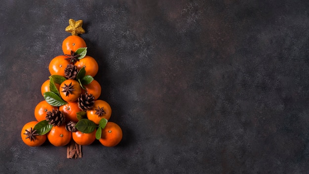 Vista superior da forma de árvore de natal feita de tangerinas e pinhas com espaço de cópia