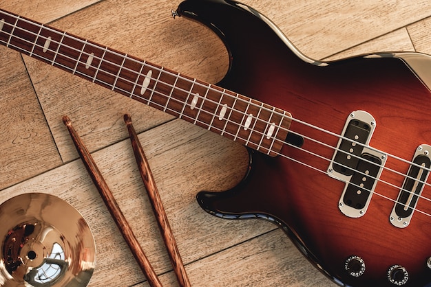 Foto vista superior da guitarra eletrônica com varas de madeira e prato dourado deitado sobre fundo de madeira. instrumentos musicais. equipamento musical