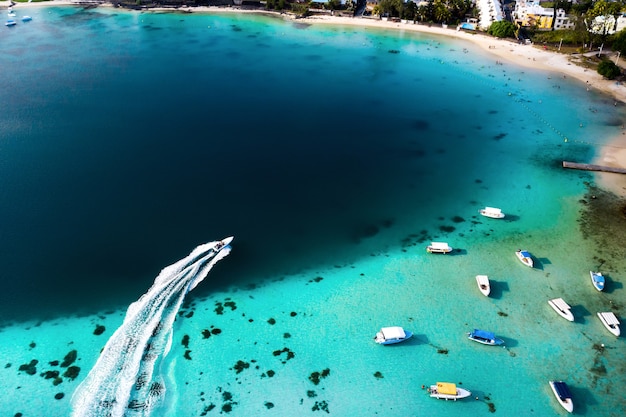 Vista superior da lagoa Blue Bay da Maurícia. Um barco flutua em uma lagoa turquesa.