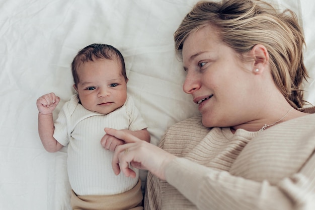 Vista superior da mãe e do bebê recém-nascido deitado na cama felizes juntos