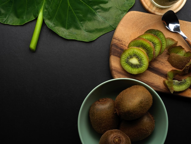 Vista superior da mesa da cozinha preta com kiwis frescos, folha verde e espaço de cópia