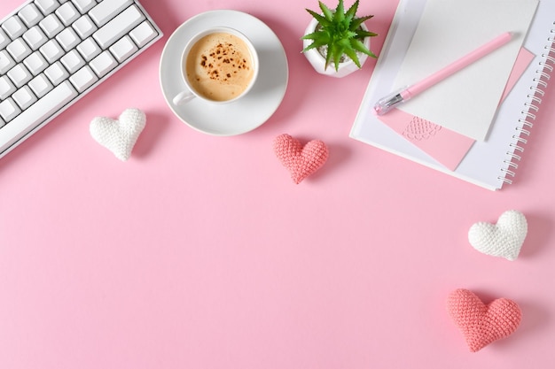 Vista superior da mesa de escritório Atmosfera romântica Um notebook com uma xícara de café e um teclado em um fundo rosa