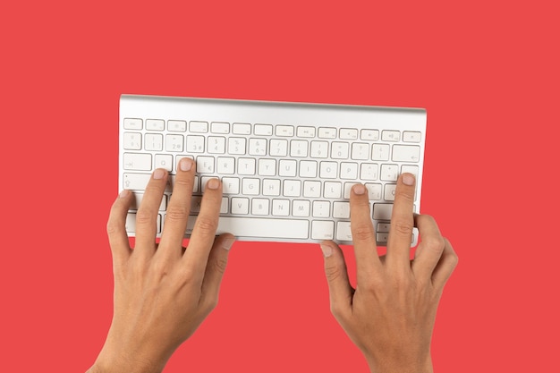 Vista superior da mesa de escritório com teclado e mão em fundo vermelho