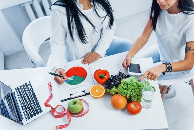 Vista superior da nutricionista que dá consulta ao paciente dentro de casa, no escritório.