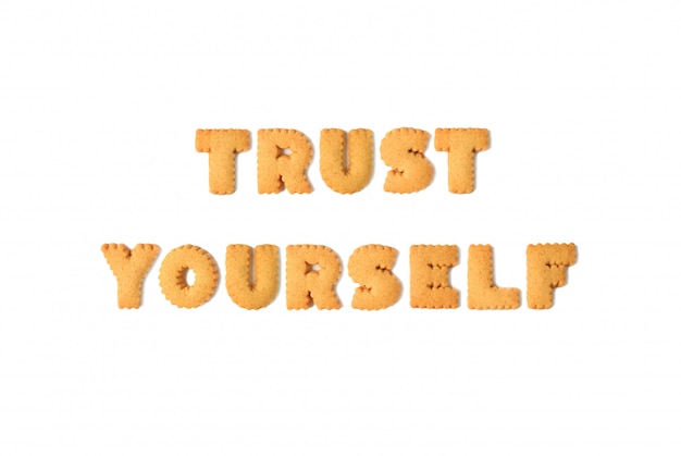 Vista superior da palavra confiar em si mesmo escrito com biscoitos em forma de alfabeto, isolados no fundo branco