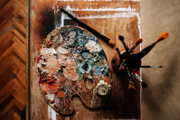 Vista superior da paleta e das escovas do artista em um fundo de madeira.