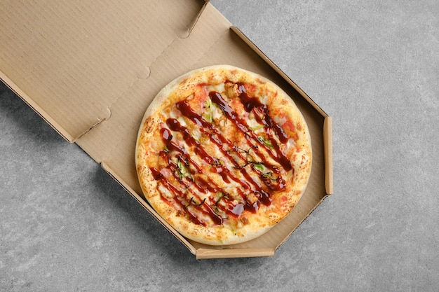 Vista superior da pizza de churrasco com bacon e cebolinha em caixa de papelão