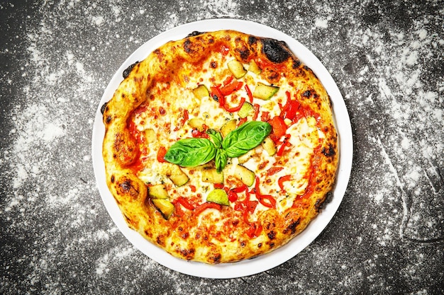 Vista superior da pizza vegetariana com abobrinha e pimenta em fundo escuro