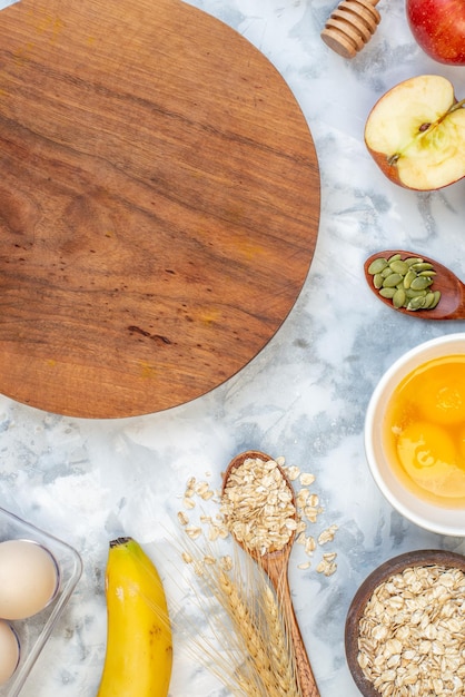 Vista superior da placa redonda de madeira e ingredientes para a alimentação saudável em mesa branca manchada