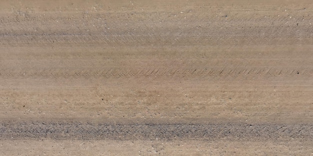 Vista superior da superfície da estrada de cascalho feita de pequenas pedras e areia com vestígios de pneus de carro
