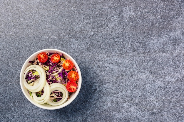 Vista superior da tigela de salada colorida saudável com tomate fresco misturado folhas vegetais em um prato