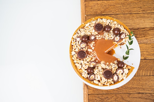 Vista superior da torta redonda com caramelo salgado e nozes na seção pedaço de bolo no carrinho de madeira conceito de cozimento caseiro