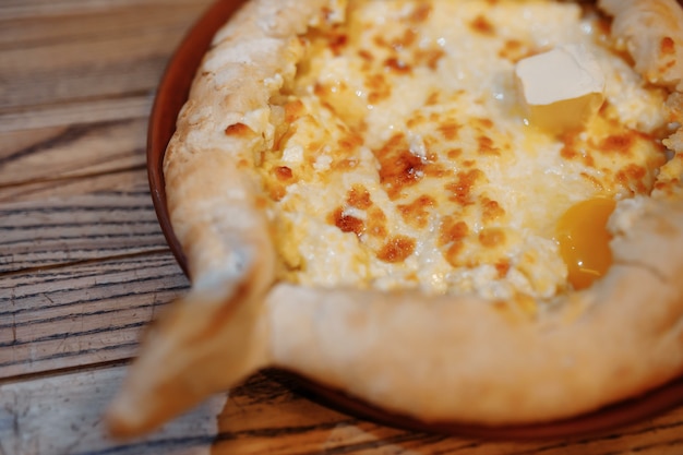 Vista superior da tradicional torta de adjarian khachapuri aberta com suluguni de queijo salgado derretido e ovo