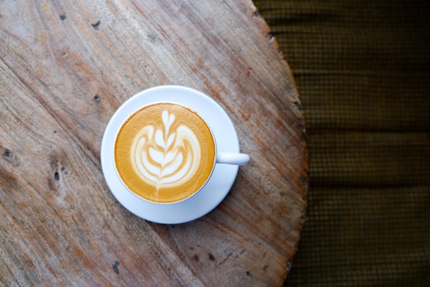Vista superior da xícara branca de cappuccino com latte art na mesa de madeira