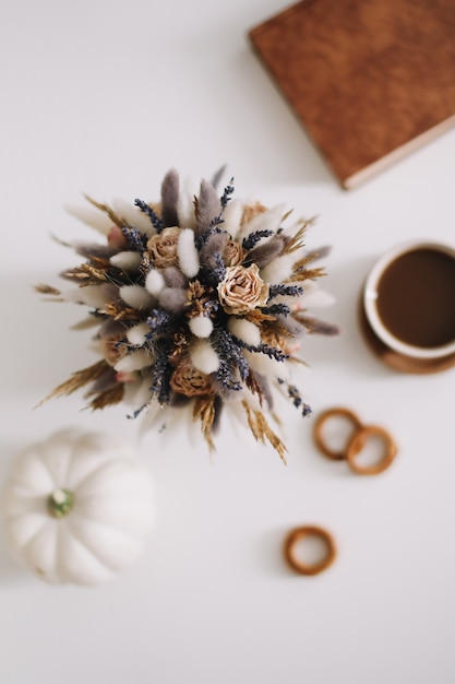 Vista superior da xícara de café e flores secas em fundo branco Flat lay