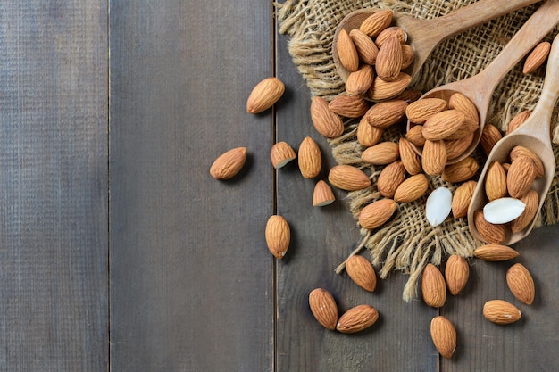 Vista superior das amêndoas em colher de madeira no fundo de madeira Eles são altamente nutritivos e ricos em gorduras saudáveis ou antioxidantes de colesterol HDL de lipoproteína de alta densidade