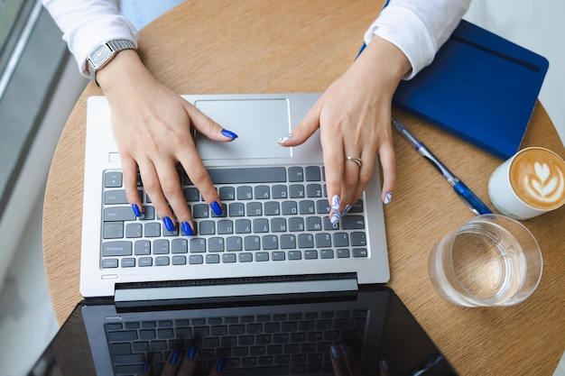 Vista superior das mãos da mulher usando laptop em um café