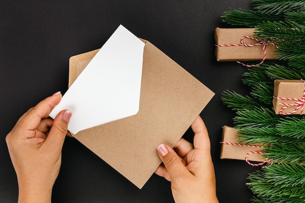 Vista superior das mãos de mulher, enviando carta com desejos de Papai Noel em fundo preto com o Natal de ...