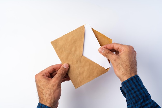 Foto vista superior das mãos masculinas abre um envelope acima do fundo branco
