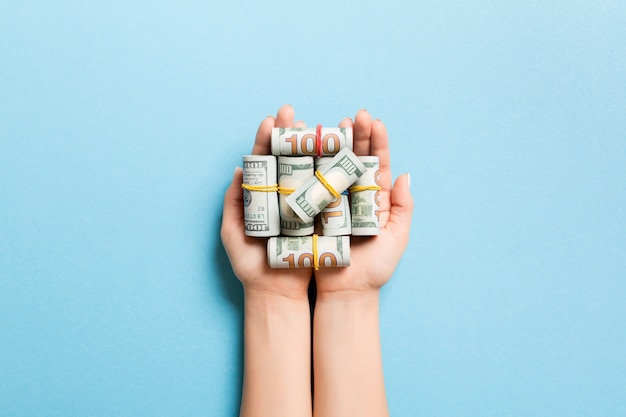 Vista superior das notas de dólar em tubos nas mãos femininas. conceito de negócios
