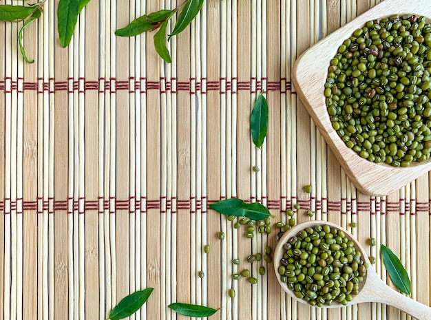 Foto vista superior das sementes de feijão mung em uma colher de pau, colocada em uma esteira japonesa