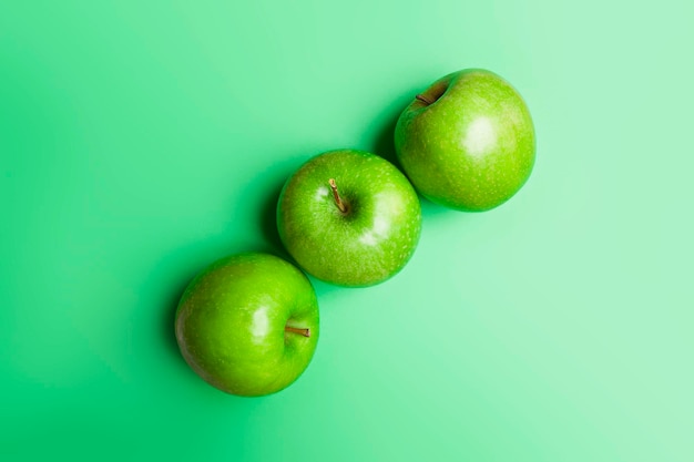Vista superior de 3 maçãs verdes sobre fundo verde