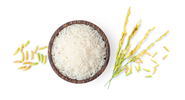 Vista superior de arroz branco e arroz em casca em uma tigela de madeira com orelha de arroz isolada no fundo branco
