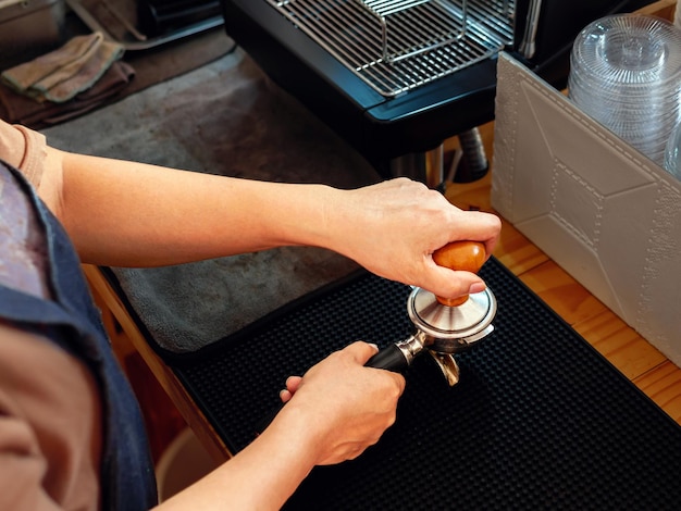 Foto vista superior de barista segurando portafilter e manipulador de café fazendo um café expresso na cafeteria