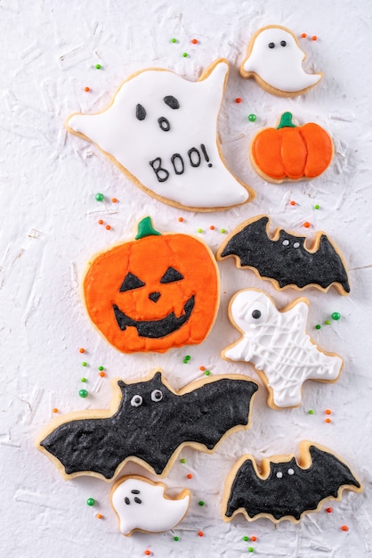 Vista superior de biscoitos de açúcar de confeiteiro de gengibre de confeiteiro de Halloween com decoração festiva em fundo branco, com espaço de cópia e layout plano leigo.