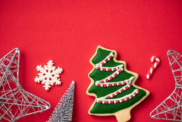 Vista superior de biscoitos de gengibre de Natal decorados com enfeites em fundo de mesa vermelha com espaço de cópia, conceito de celebração do feriado.