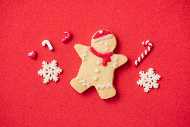 Foto vista superior de biscoitos de gengibre de natal decorados em fundo de mesa vermelha com espaço de cópia, conceito de celebração do feriado.