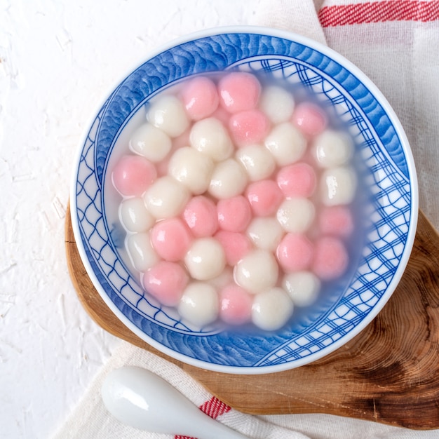 Vista superior de bolinhas de bolinho de arroz glutinoso tangyuan tang yuan vermelho e branco em uma tigela azul