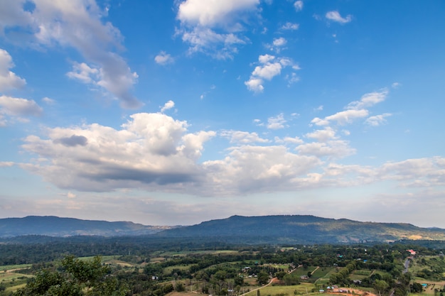 Vista superior de colinas verdes e cerca grama exuberante e céu azul com nuvens brancas