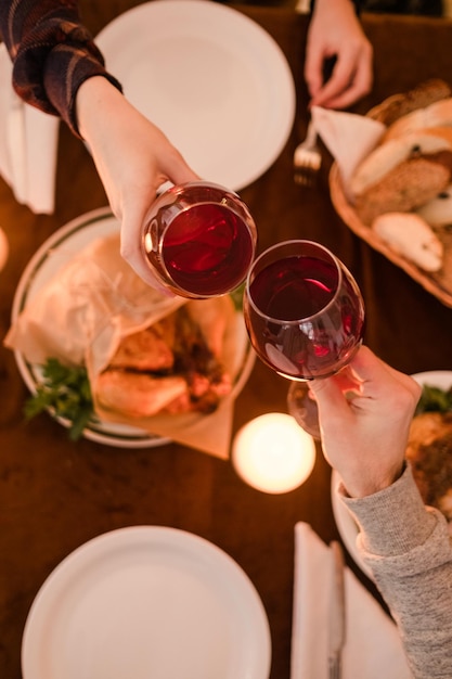 Vista superior de copos de vinho tilintando de casal Data de jantar para dois Fundo de luzes românticas Conceito de amor e comida