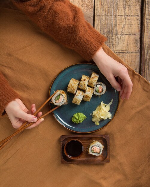 Foto vista superior de deliciosos rolos de sushi com ingredientes na mesa de madeira