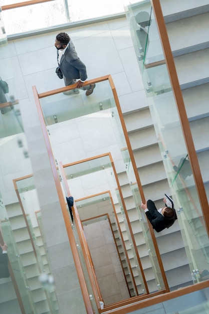 Vista superior de executivos modernos movendo-se na escada do centro de escritórios enquanto chegam ao local de trabalho
