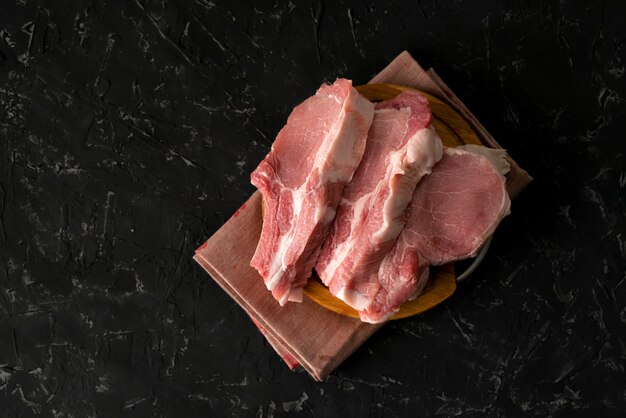 Vista superior de fatias crus de carne crua, corte a carne de porco em uma placa de madeira