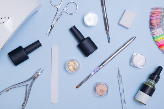 Vista superior de ferramentas e materiais para manicure moderna e extensão de unhas. Knolling sobre um fundo azul. Ferramentas de manicure planas