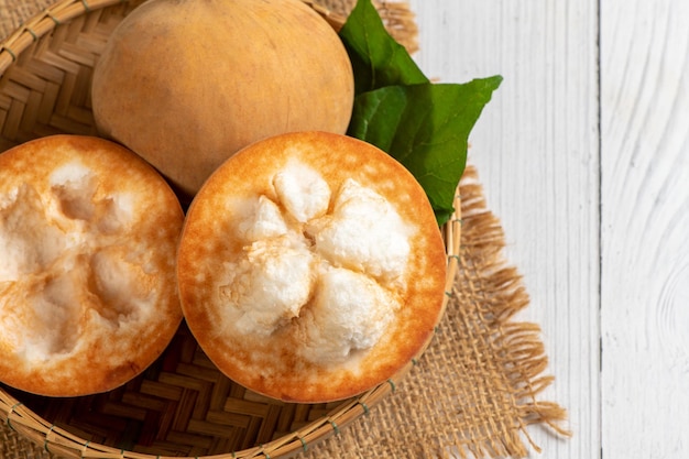 Vista superior de frutas frescas de Santol na cesta de bambu e sobre fundo branco de madeira