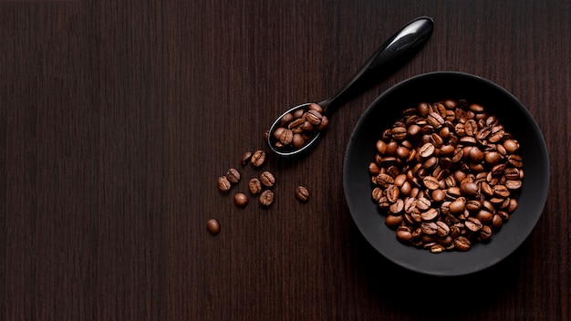 Vista superior de grãos de café torrados com colher e cópia de espaço