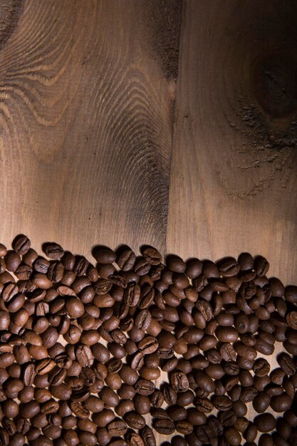Vista superior de grãos de café torrados frescos em uma mesa de madeira com espaço de cópia