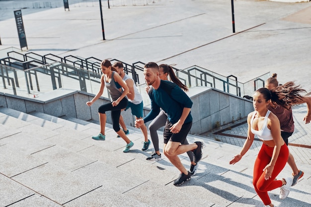 Vista superior de jovens em roupas esportivas correndo enquanto se exercitam nas escadas ao ar livre